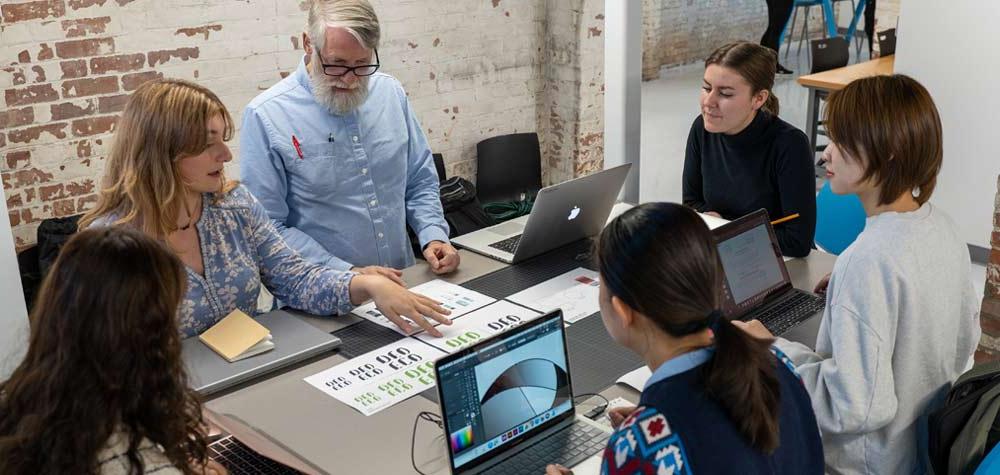 a student showing another student something on a laptop